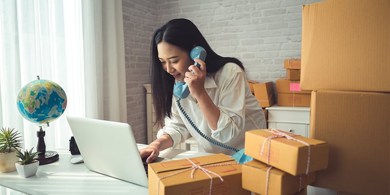 woman on the phone in her office surrounded by moving boxes