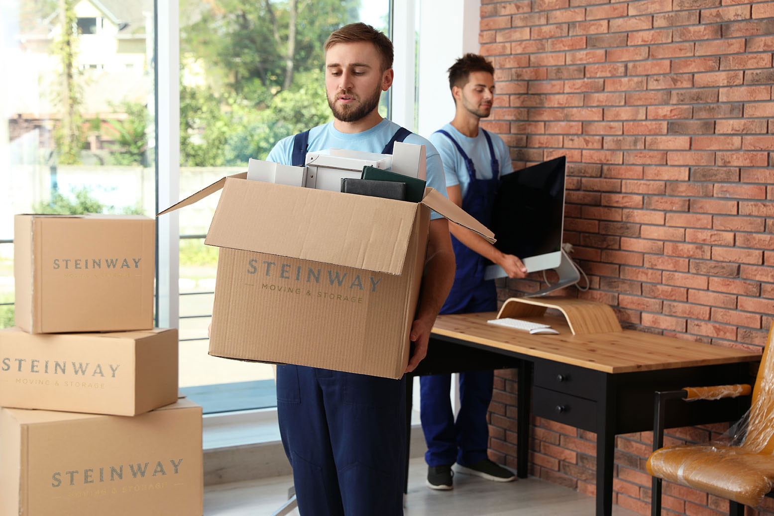 Movers carrying boxes and office equipment